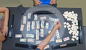 Friends playing to a strategy game board on a table. Blocks of number and statistic for score and win in a tabletop at home. Hands