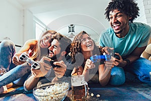 Friends playing with video games. Young people sitting in the living room and playing together