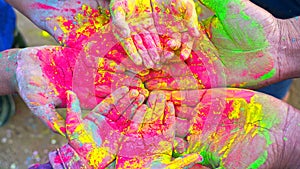 Friends putting their hands together in a sign of unity and teamwork. Holi colors festival. Friendship concept