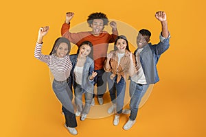 Friends with raised fists in excitement on orange background