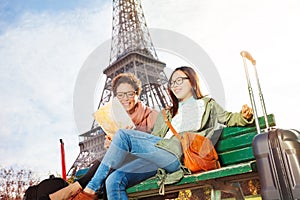 Friends reading map of Paris sitting on the bench