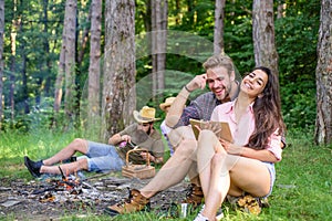 Friends relaxing near campfire after day hiking or gathering mushrooms. Summer vacation forest. Company friends couples