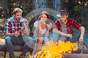 Friends relaxing near campfire after day hiking or gathering mushrooms. Tourism concept. Best friends spend leisure
