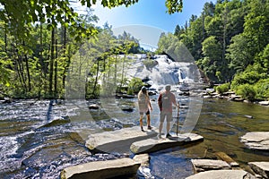 Friends relaxing by the waterfall on hiking trip.