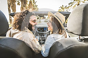 Happy couple driving convertible car enjoying summer vacation