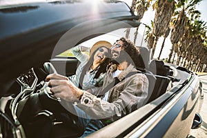 Happy couple driving convertible car enjoying summer vacation