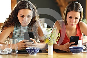 Friends in a restaurant ignoring each other using phones