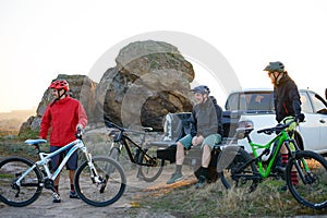 Friends Resting near Pickup Off Road Truck after Bike Riding in the Mountains at Sunset. Adventure and Travel Concept.