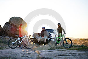 Friends are Resting on Pickup Offroad Truck after Bike Riding in the Mountains at Sunset. Adventure and Travel Concept