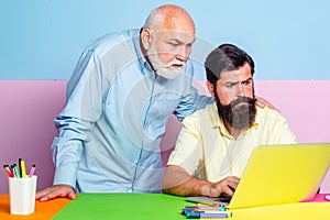 Friends senior father and adult son taking a break after meeting session and watching something on laptop notebook.