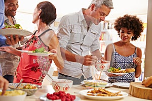 Friends serving themselves food and talking at dinner party