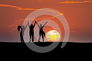 Friends silhouette over the dune with sun in the background