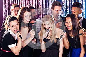 Friends singing into microphones at karaoke party