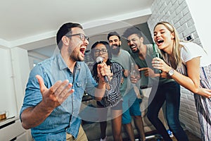 Friends singing together at home. Karaoke party concept