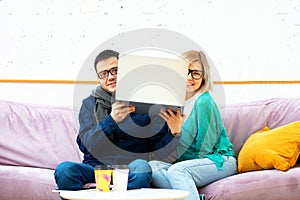 Friends sit on the couch, chatting and using a desktop computer.