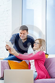 Friends sit on the couch, chatting and using a tablet computer.