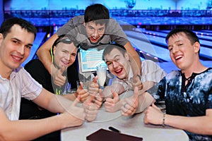 Friends sit at table and thumb up in bowling