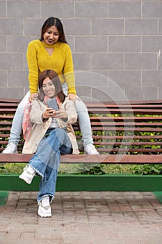 Friends sitting on a bench posing while taking a selfie
