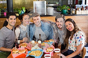 Friends sitting by food and drink served on table in restaurant