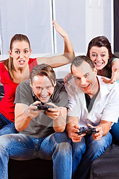 Friends sitting in front of game console box