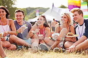 Friends sitting on the grass eating at a music festival