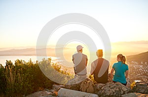 Friends sitting on a mountain trail watching the sunrise together