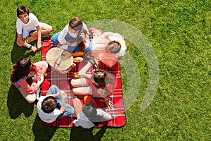 Friends sitting near picnic basket on green meadow