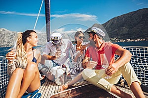 Friends sitting on sailboat deck and having fun.Vacation, travel, sea, friendship and people concept