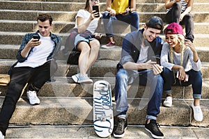 Friends sitting on the staircase using smartphones together and