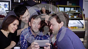 Friends sitting at the table in cafe together spending leisure time together and using digital gadget. Three handsome