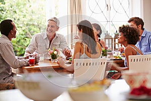 Friends sitting at a table talking during a dinner party