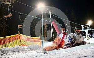 Friends skiers having fun at ski resort in the mountains in winter, skiing at night
