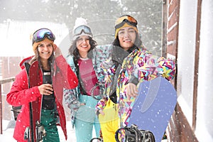 Friends with skis and snowboards wearing winter sport clothes