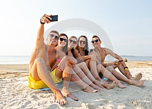 Friends with smartphones on beach