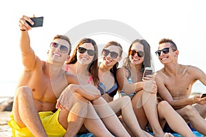 Friends with smartphones on beach