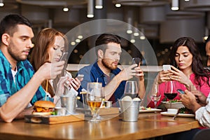 Friends with smartphones dining at restaurant