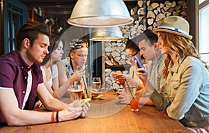 Friends with smartphones and drinks at bar