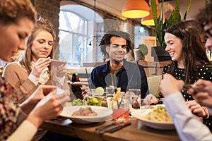 Friends with smartphones eating at restaurant