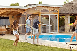 Friends splashing water on each other with squirt guns