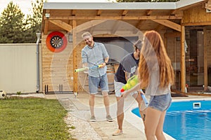 Friends splashing water on each other with squirt guns