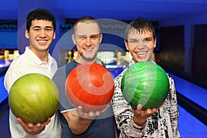 Friends stand alongside and hold balls for bowling