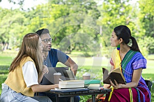 friends studying outdoor in the park on weekend, young asian people chatting together