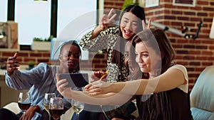 Friends in stylish home smiling for selfie photographs with wine and champagne glasses in hand