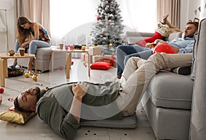 Friends suffering from hangover in messy room after New Year