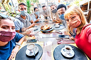 Friends taking selfie at coffee bar - People having fun together at cafeteria covered by face masks - New normal lifestyle concept