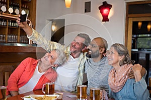 Friends taking selfie with mobile phone in bar