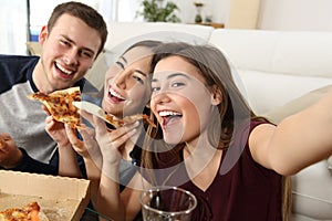 Friends taking selfies and eating pizza