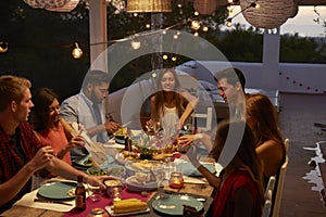 Friends talking at a dinner party on a patio, elevated view