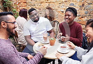 Friends talking over coffee in a trendy cafe courtyard