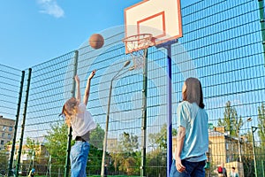 Friends teenagers playing street basketball, outdoor playground court